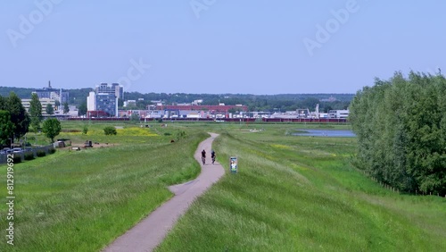 Twee wielrenners rijden op de dijk vlakbij Arnhem in Nederland. Ze geven elkaar een boks met hun hand en slaan af.  photo