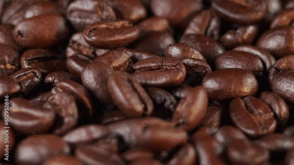 Roasted coffee beans dolly shot. Aromatic coffee beans move slowly. Slide slow motion close-up of whole roasted coffee beans.