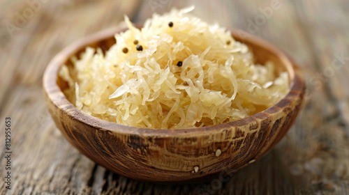 Fresh sauerkraut with caraway seeds in a rustic wooden bowl on wooden table in close-up shot