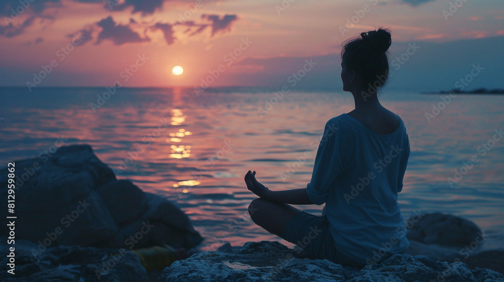 Fototapeta premium Woman meditates by the ocean at sunset, finding peace. 