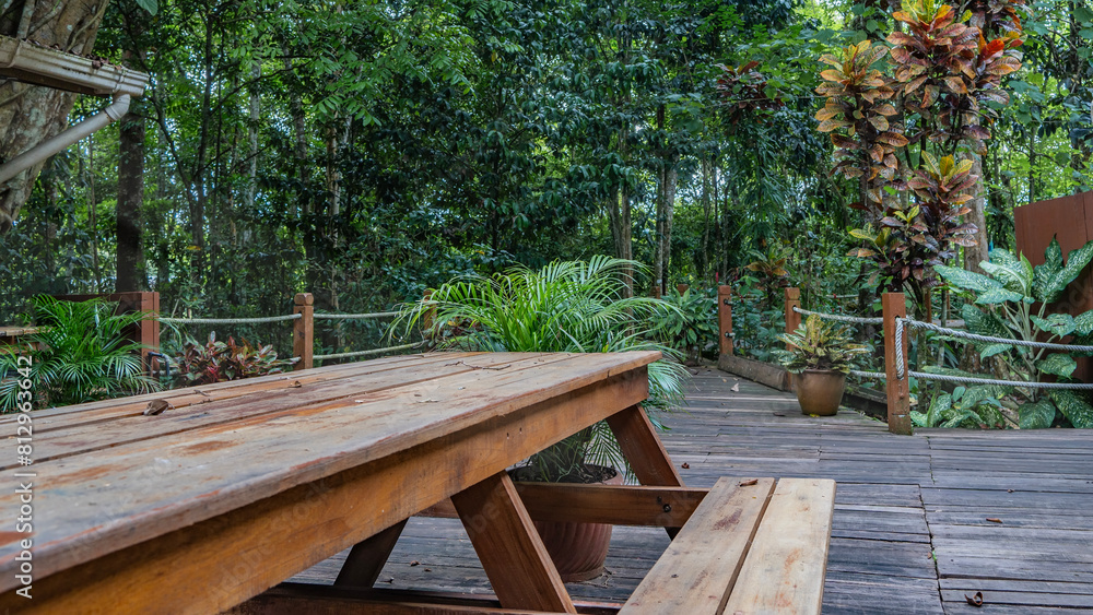 A place to relax in the rain forest lodge. Wooden benches and tables are set on the boardwalk outdoor terrace. Rope railings along the path. Lush tropical vegetation all around. Malaysia. Borneo. A place to relax in the rain forest lodge. Wooden benches and tables are set on the boardwalk outdoor terrace. Rope railings along the path. Lush tropical vegetation all around. Malaysia. Borneo.