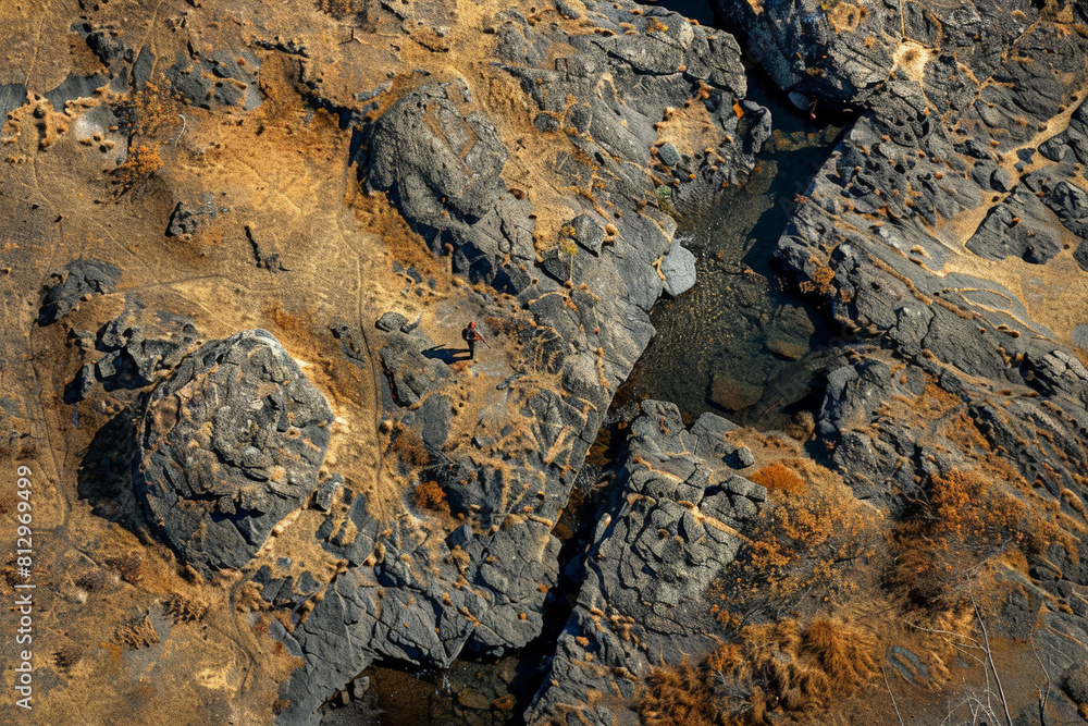 Aerial view of a hunter stealthily navigating through a rugged terrain, blending into the natural environment Aerial view of a hunter stealthily navigating through a rugged terrain, blending into the natural environment