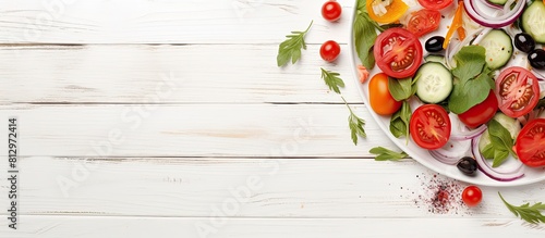 Top view copy space image of a healthy vegetarian meal featuring a fresh vegetable salad composed of tomatoes lettuce onion and cheese beautifully presented on a white wooden background