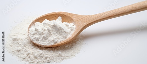 A wooden spoon with flour is positioned against a white background creating a copy space image