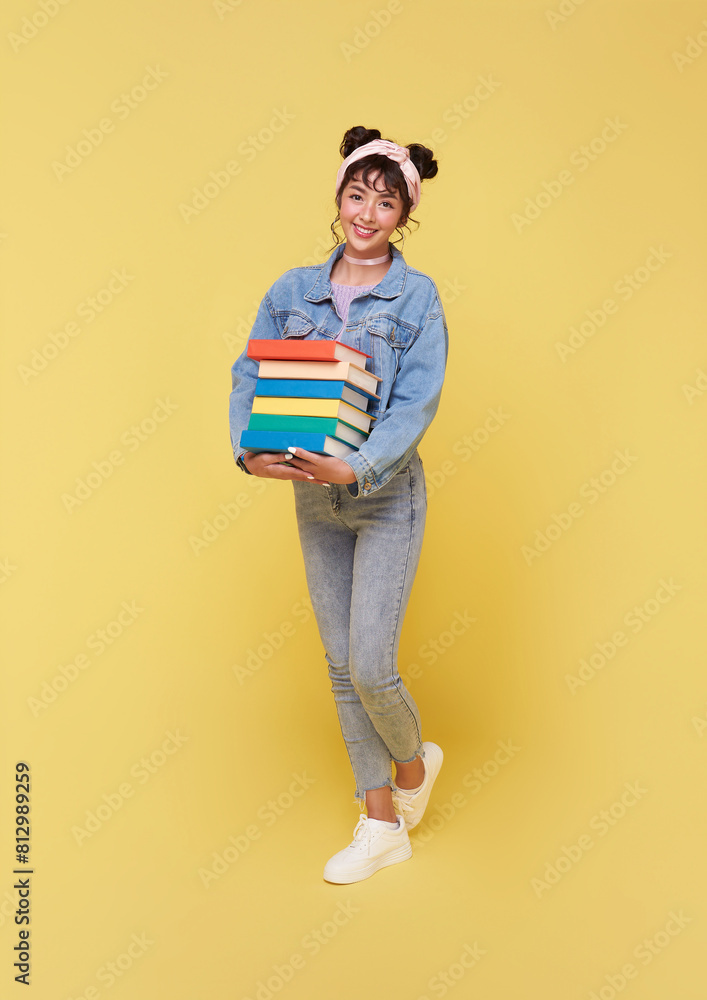 Portrait of happy smiling young Asian college student holding books ready to school isolated on yellow background. Portrait of happy smiling young Asian college student holding books ready to school isolated on yellow background.
