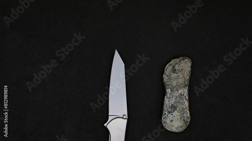 A modern knife, and a Stone Age knife. Black background. Copy space. 