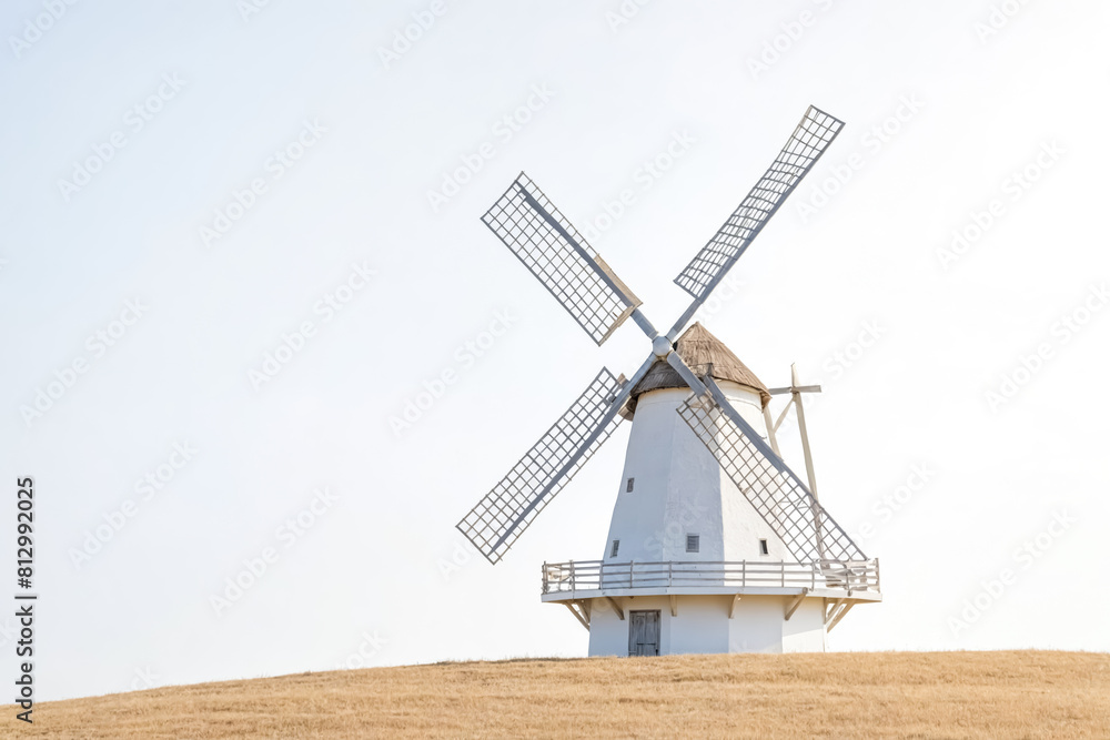 Traditional Windmill on a Golden Hill Under a Clear Sky Traditional Windmill on a Golden Hill Under a Clear Sky