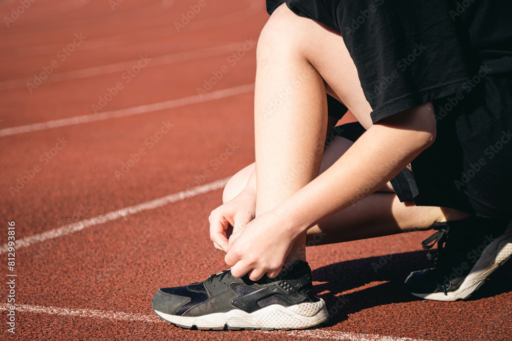 Close-up, teenage girl tying her shoelaces at the stadium before jogging, copy space.