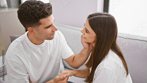 Affectionate couple holding hands in a cozy modern living room, expressing love and togetherness, evoking warm, romantic emotions. photo