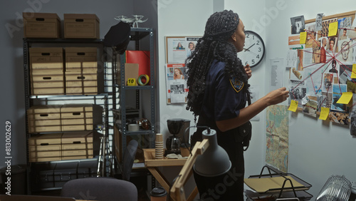 A policewoman and her male colleague analyze evidence in a cluttered investigation room at a police department.