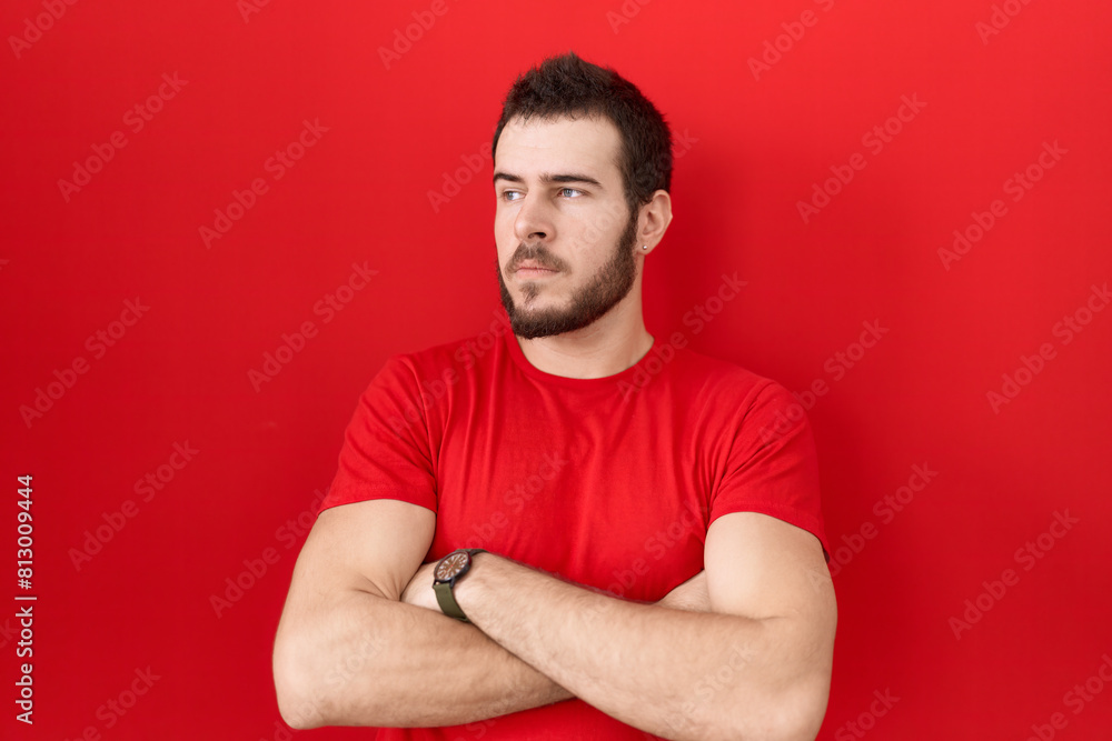 Young hispanic man wearing casual red t shirt looking to the side with arms crossed convinced and confident Young hispanic man wearing casual red t shirt looking to the side with arms crossed convinced and confident