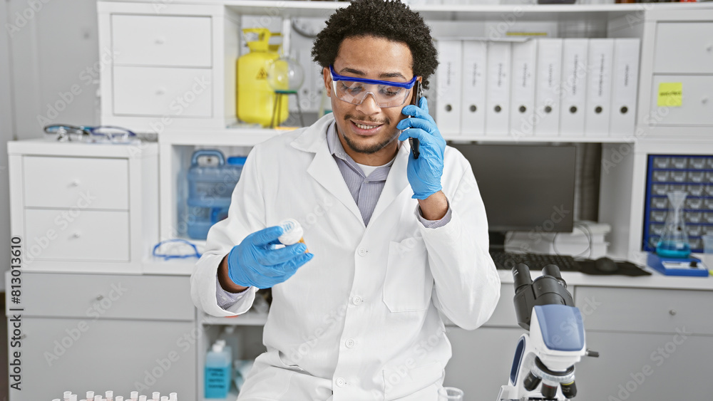 A man examines medication while on a phone in a lab, wearing a labcoat, gloves, and safety goggles. A man examines medication while on a phone in a lab, wearing a labcoat, gloves, and safety goggles.