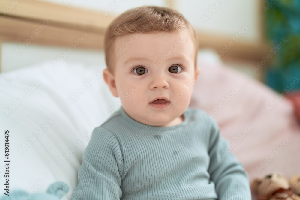 Adorable toddler sitting on bed with dolls at bedroom Adorable toddler sitting on bed with dolls at bedroom