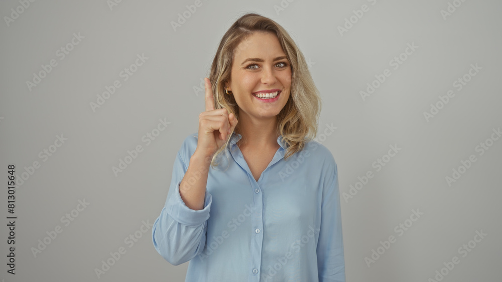 Young caucasian woman having an idea on a white background with a cheerful expression, blonde hair, and a blue shirt. Young caucasian woman having an idea on a white background with a cheerful expression, blonde hair, and a blue shirt.