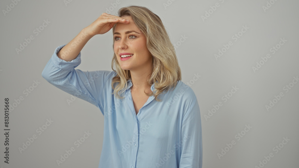 A beautiful young blonde woman in a blue shirt peers into the distance against a white background. A beautiful young blonde woman in a blue shirt peers into the distance against a white background.