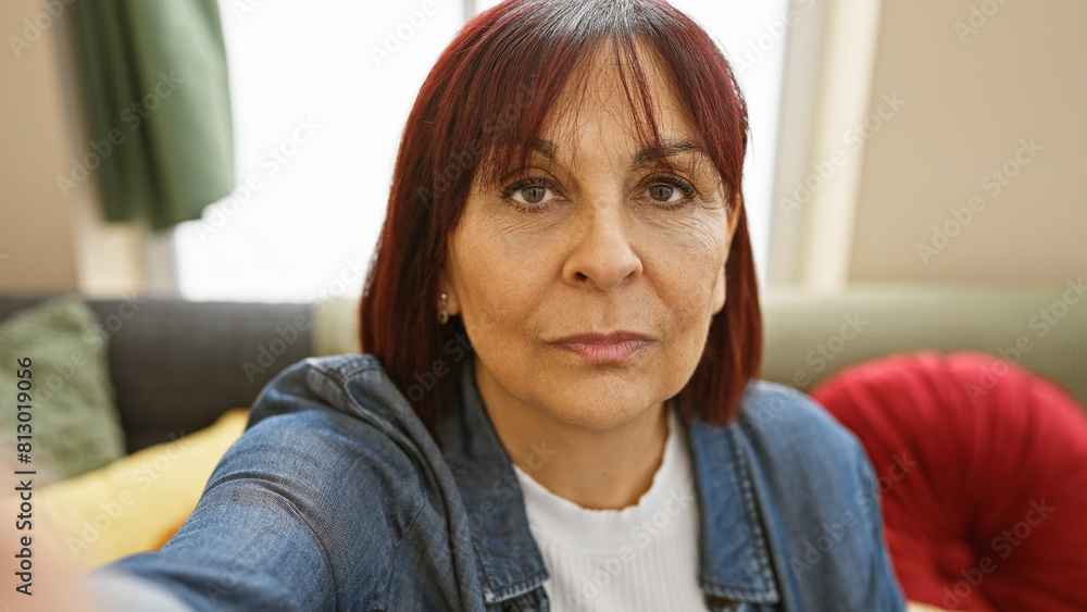 A mature hispanic woman sits comfortably at home, projecting warmth and confidence. A mature hispanic woman sits comfortably at home, projecting warmth and confidence.