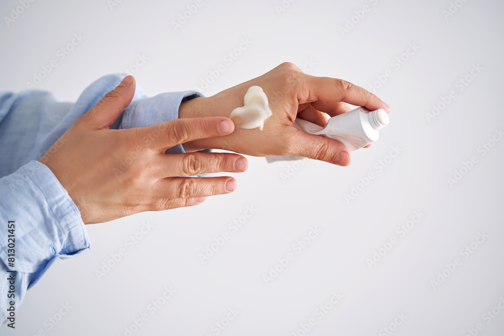 Hands in a blue shirt hold a tube of cream. Hands in a blue shirt hold a tube of cream.