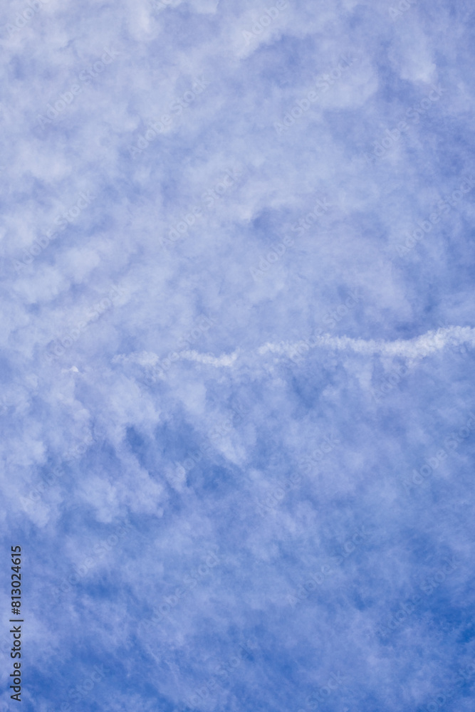 Vast blue sky with soft, textured clouds and a singular airplane trail cutting across the serene expanse. Vast blue sky with soft, textured clouds and a singular airplane trail cutting across the serene expanse.