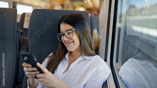 Young beautiful hispanic woman smiling using smartphone sitting inside train wagon © Krakenimages.com