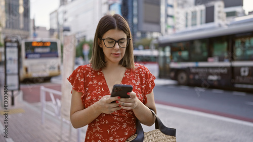 Beautiful hispanic woman with glasses in tokyo, digital connection via smartphone on city streets photo