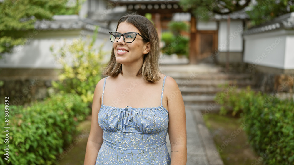 Hispanic female, radiating beauty and joy with glasses, looking around with cheerful expression at kyoto temple, standing confidently amidst japanese architecture, basking in the serenity.