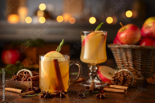 Mulled cider with apples  cinnamon  rosemary  and anise on a background of burning candles.