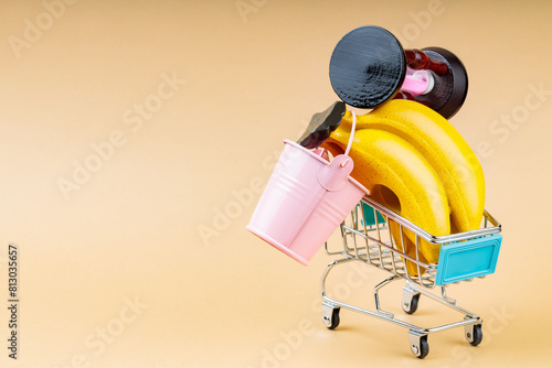 Overfilled Shopping Cart on Beige Background, Overconsumption Concept, Copy Space photo