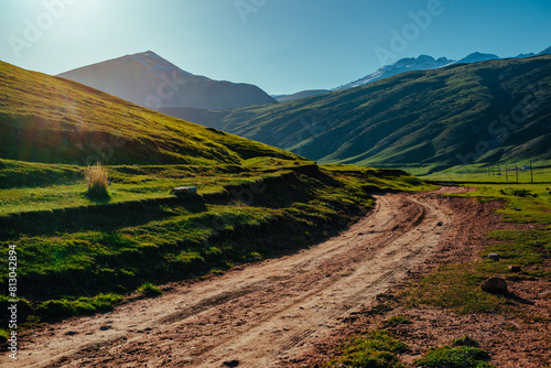Picturesque mountain valley with dirt road at sunset