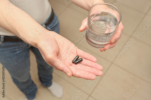 woman with pills in her palm and a glass of water
