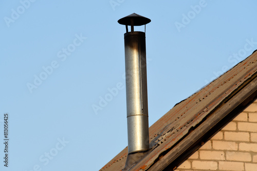 A chimney on a blue sky background. A shiny iron chimney.