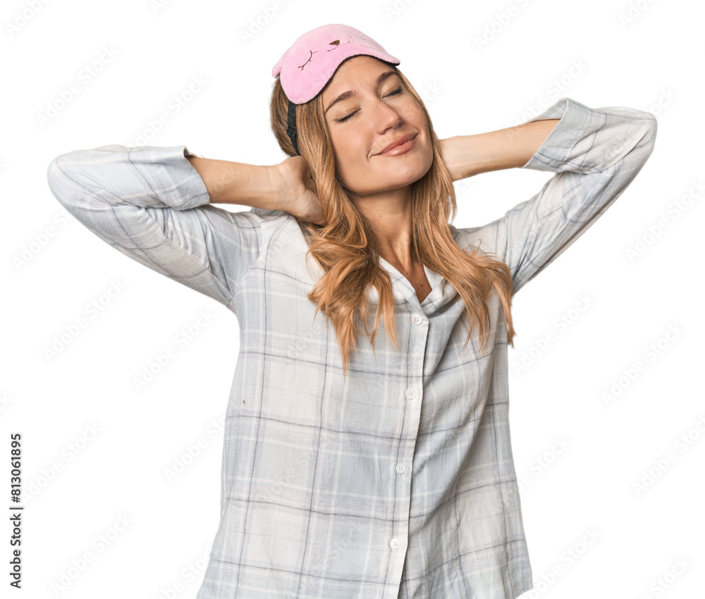 Blonde in pajamas with sleep mask stretching arms, relaxed position. Blonde in pajamas with sleep mask stretching arms, relaxed position.