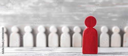 Red wooden figure leading a group of white figures photo