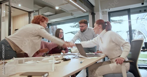Enthusiastic business team members put their hands together, celebrating a successful project completion in a modern office setting, their shared excitement and unity reflecting their strong teamwork.