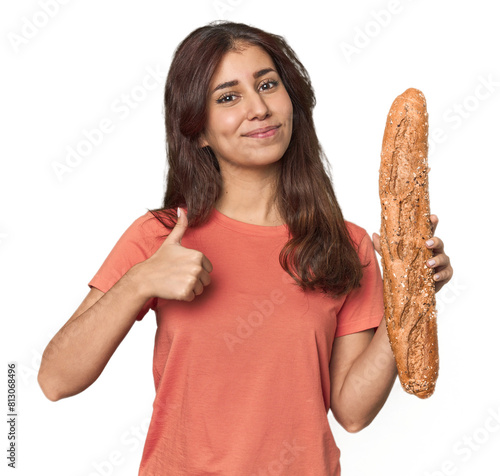 Middle Eastern woman holding bread loaf smiling and raising thumb up