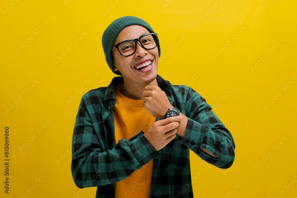 Asian student in casual university outfit, wearing eyeglasses, a beanie, and a wristwatch, isolated on a yellow background Asian student in casual university outfit, wearing eyeglasses, a beanie, and a wristwatch, isolated on a yellow background