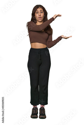Middle Eastern woman, full body studio shocked and amazed holding a copy space between hands.