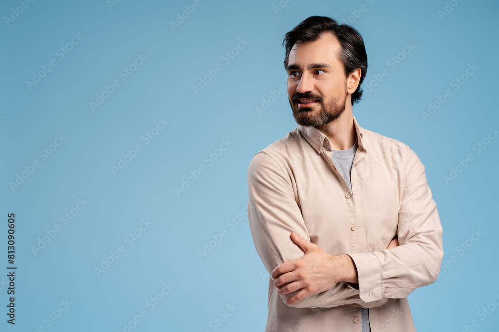 Portrait of young man with arms crossed, posing in studio, isolated on blue background. Copy space Portrait of young man with arms crossed, posing in studio, isolated on blue background. Copy space