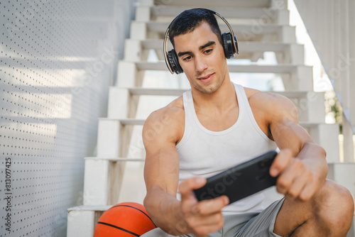 Portrait of man use headphones and smart phone to play video games © Miljan Živković