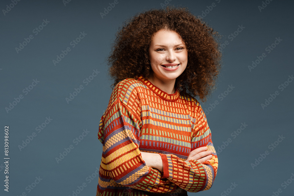 Excited attractive woman with curly hair wearing casual sweater looking at camera with arms crossed Excited attractive woman with curly hair wearing casual sweater looking at camera with arms crossed