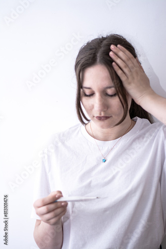 Woman measuring tempreture with a thermometer  photo