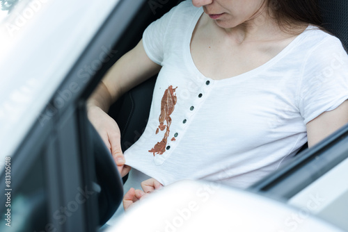 Young woman driving spilled cosmetic cream or food on a white t-shirt. Cosmetic stains on the white clothes. daily life stain and cleaning concept. 
