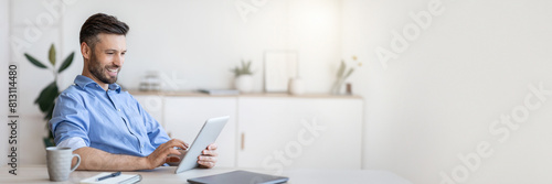 Handsome Young Businessman Using Digital Tablet At Workplace In Office, Browsing New Application Or Social Media, Free Space
