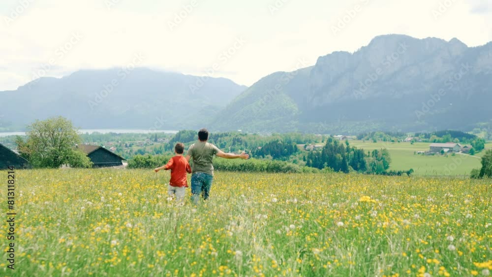 Happiness of dad and son running in blooming alpine mountains Happiness of dad and son running in blooming alpine mountains