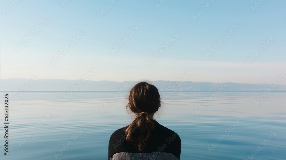 Woman black sweater sitting peacefully Lake Geneva contemplating morning waters Woman black sweater sitting peacefully Lake Geneva contemplating morning waters