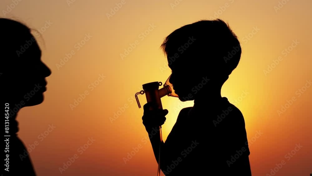 An Asian mother puts a nebulizing mask on her child's face at sunset. Healthcare and nebulizer concept. An Asian mother puts a nebulizing mask on her child's face at sunset. Healthcare and nebulizer concept.