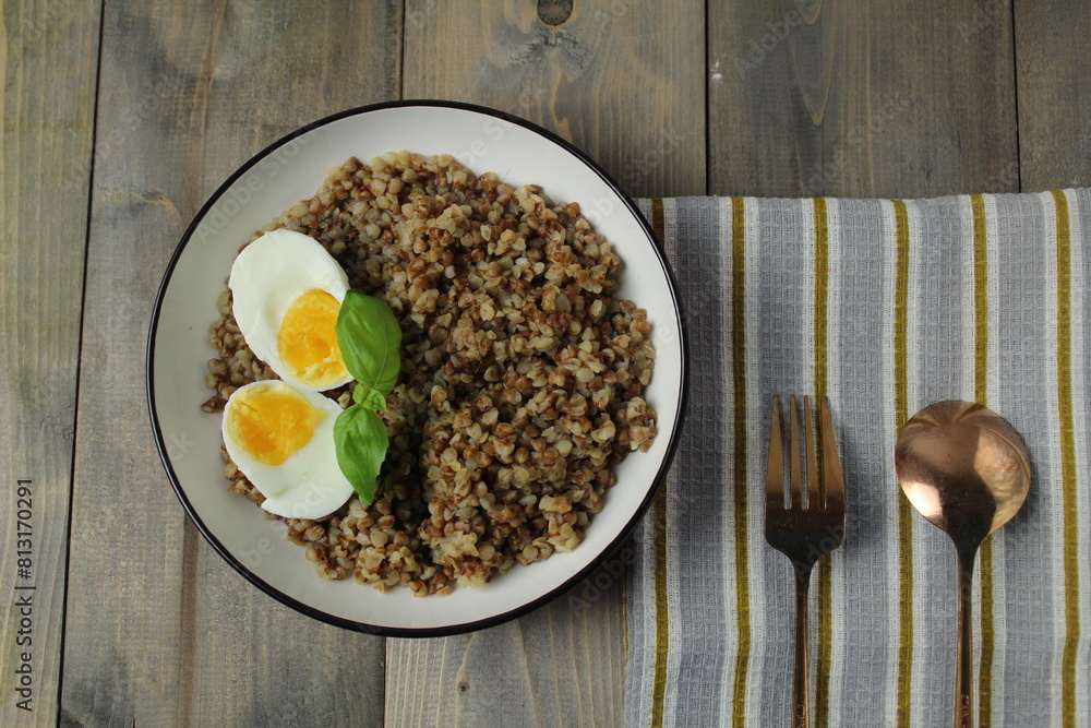 buckwheat, boiled egg, herbs, basil, spoon, fork on a napkin. View from above. The concept of a delicious breakfast lunch. Slavic dishes buckwheat, boiled egg, herbs, basil, spoon, fork on a napkin. View from above. The concept of a delicious breakfast lunch. Slavic dishes