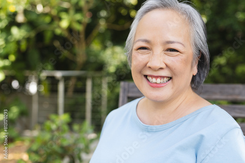 Outdoors, Asian senior female standing, smiling with greenery behind, copy space