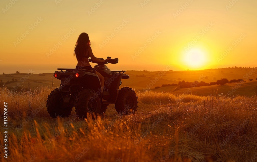 Fototapeta premium A woman is driving an ATV in a field with a beautiful sunset in the background. The scene is peaceful and serene, with the woman enjoying the ride and the beautiful view