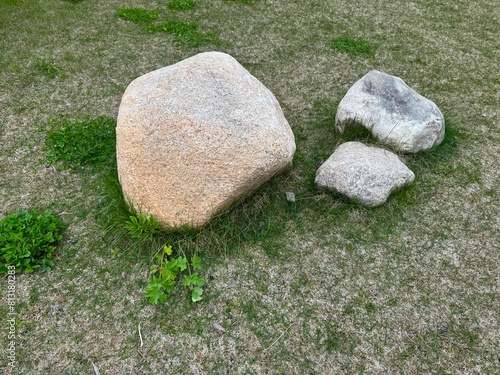 Three rocks of varying sizes on a patch of grass