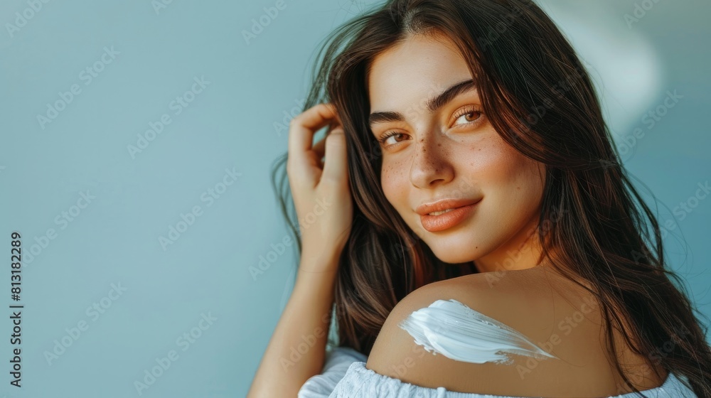 Portrait of gorgeous young woman with long hair applying body cream on her shoulder. Body lotion, moisturizing cream, sun protection cosmetics concept Portrait of gorgeous young woman with long hair applying body cream on her shoulder. Body lotion, moisturizing cream, sun protection cosmetics concept